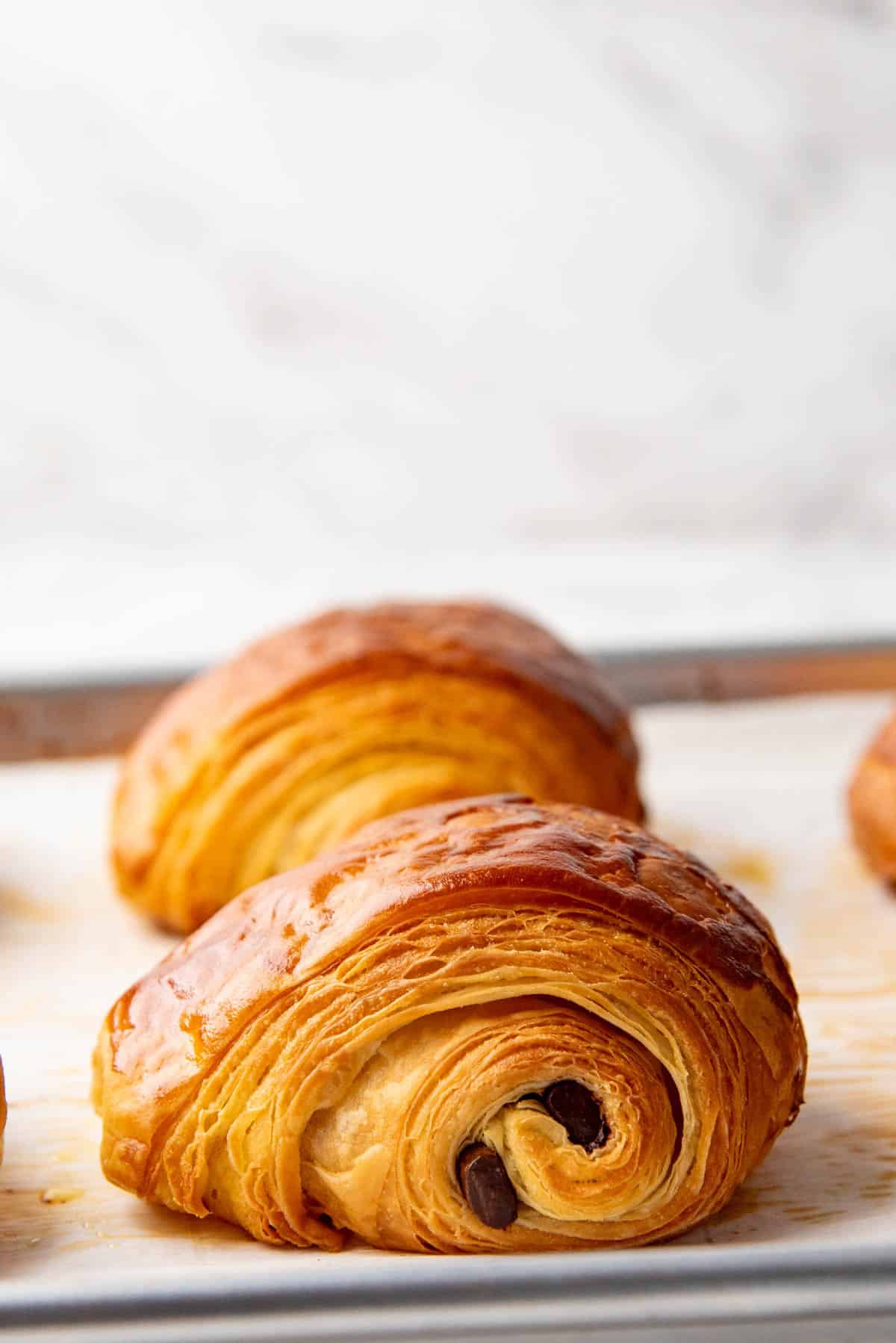 Close up of a pain au chocolat showing beautiful flaky layers and chocolate sticks in the middle.