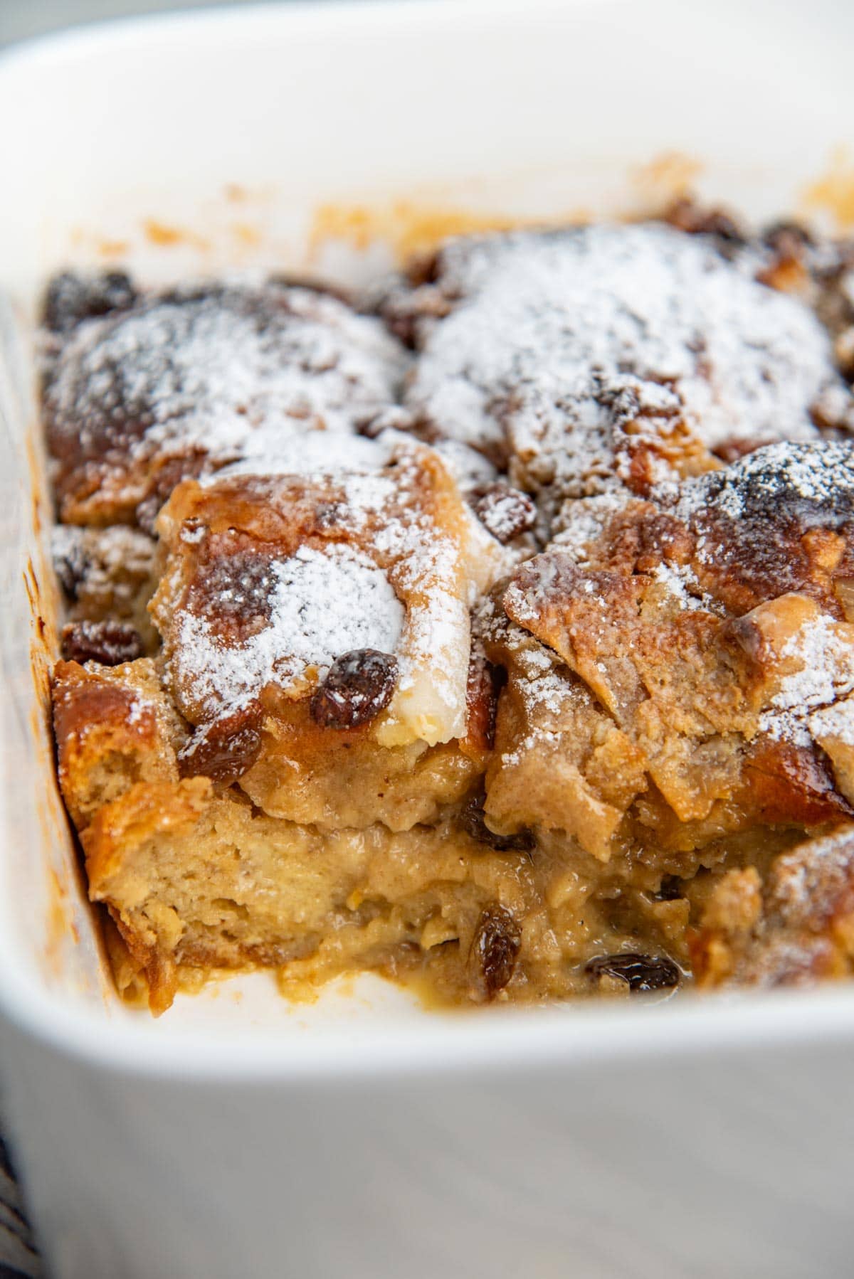 Hot cross bun bread pudding in a baking dish with a serving taken out to show the rich, custardy texture.
