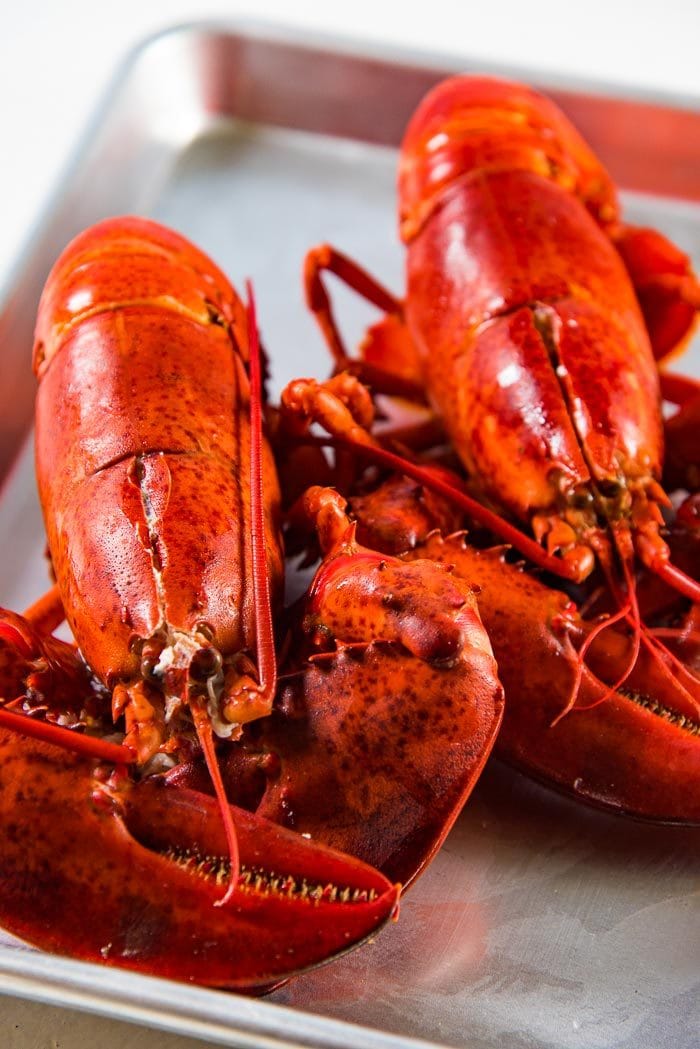 Two cooked lobsters on a baking tray.