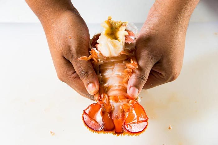 How to get the meat out from the lobster tail - The lobster tail is being pulled apart after being cracked.