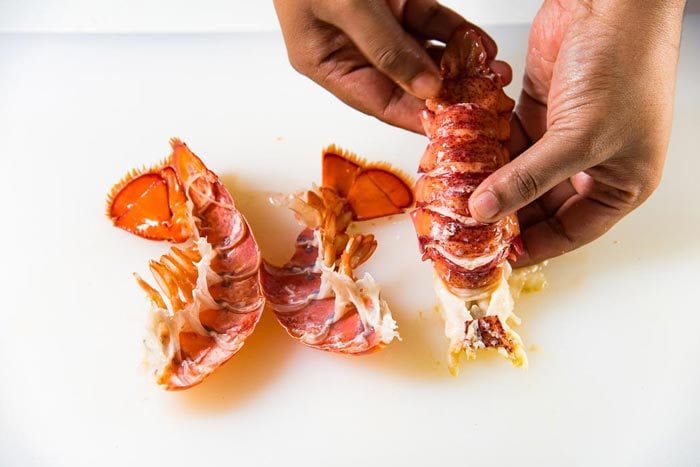 The two lobster tail shell cracked into two, with the lobster tail meat intact next to it.