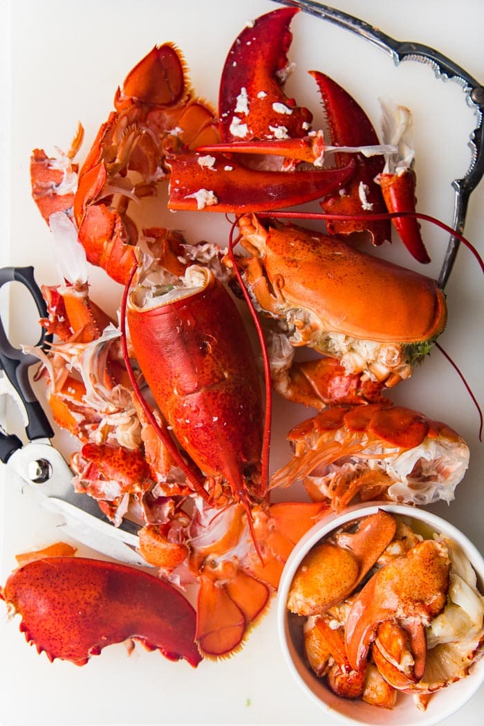 Lobster shells that have been cracked open on a white cutting board