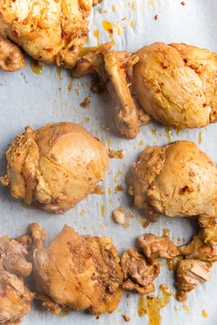 The cooked chicken thighs placed on a lined baking tray