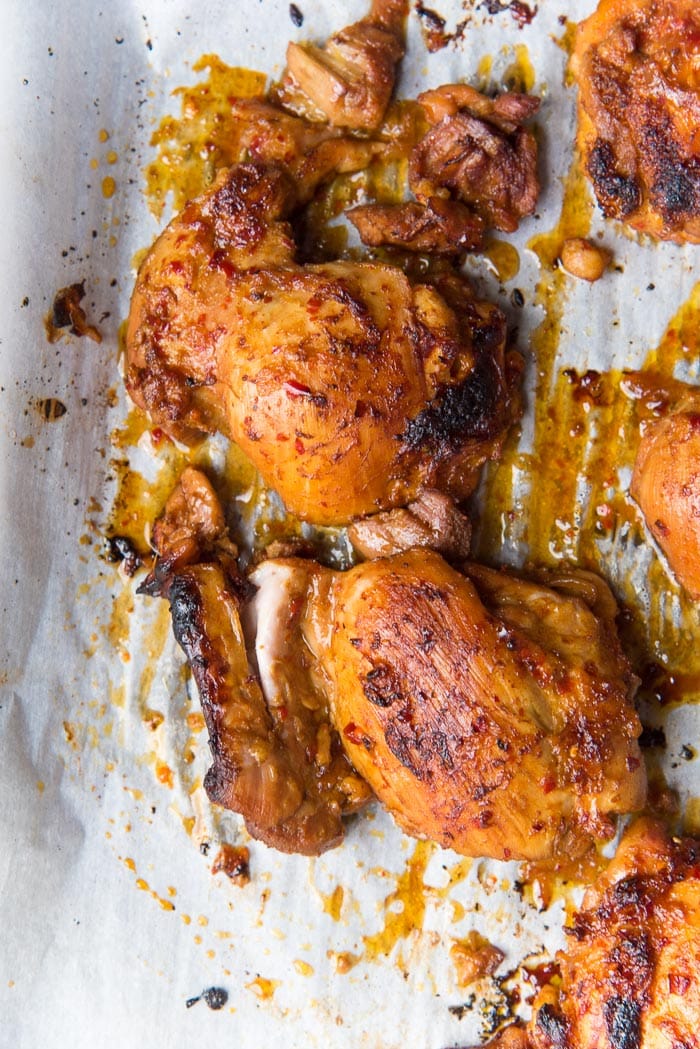 Cooked chicken thighs on a baking tray after being grilled in the oven, with some caramelization on top