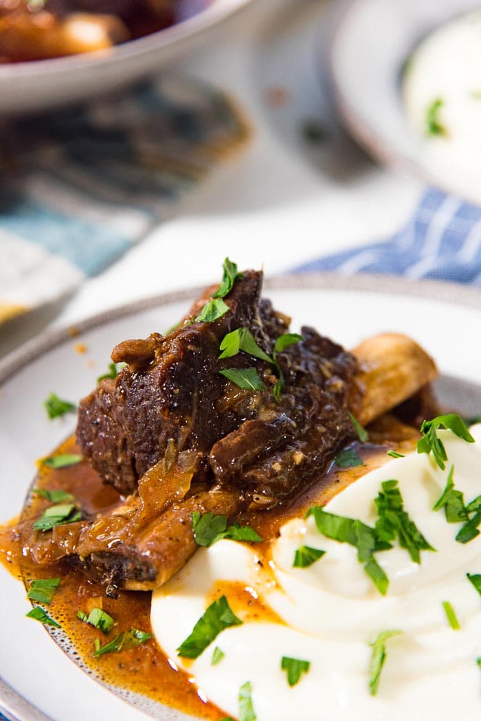 A close up of the braised instant pot short ribs with creamy mashed cauliflower with gravy on a plate. 