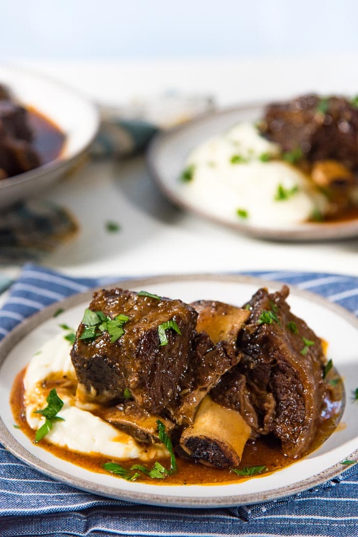 A serving of braised short ribs with no wine, served on a plate of creamy mashed cauliflower. 