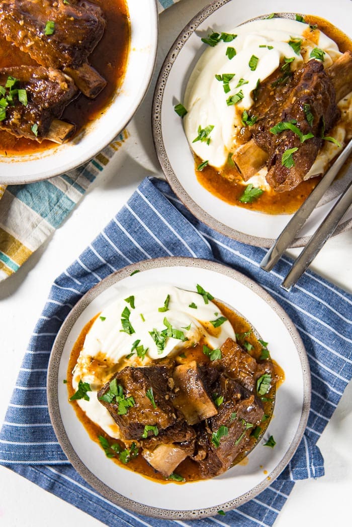 An overhead view of two plates with braised pressure cooker short ribs with creamy mashed cauliflower. 