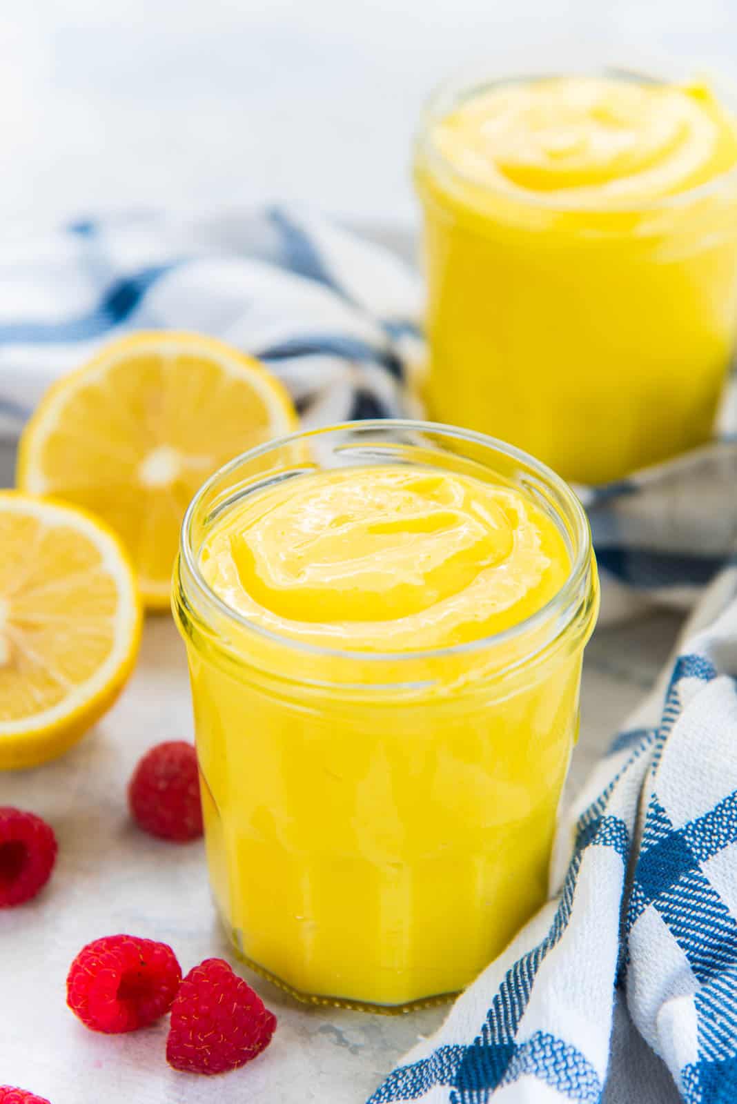 Easy, thick and tangy homemade lemon curd in two jars, on a table top