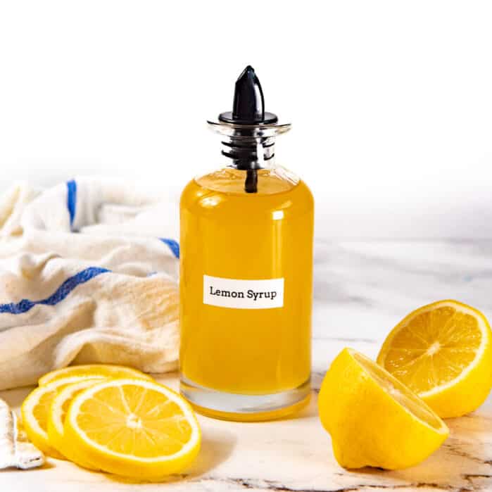 Square image of a syrup bottle filled with a yellow lemon syrup liquid.