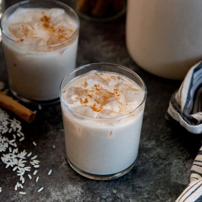 Glass of Mexican horchata served with ice and topped with a sprinkling of cinnamon.