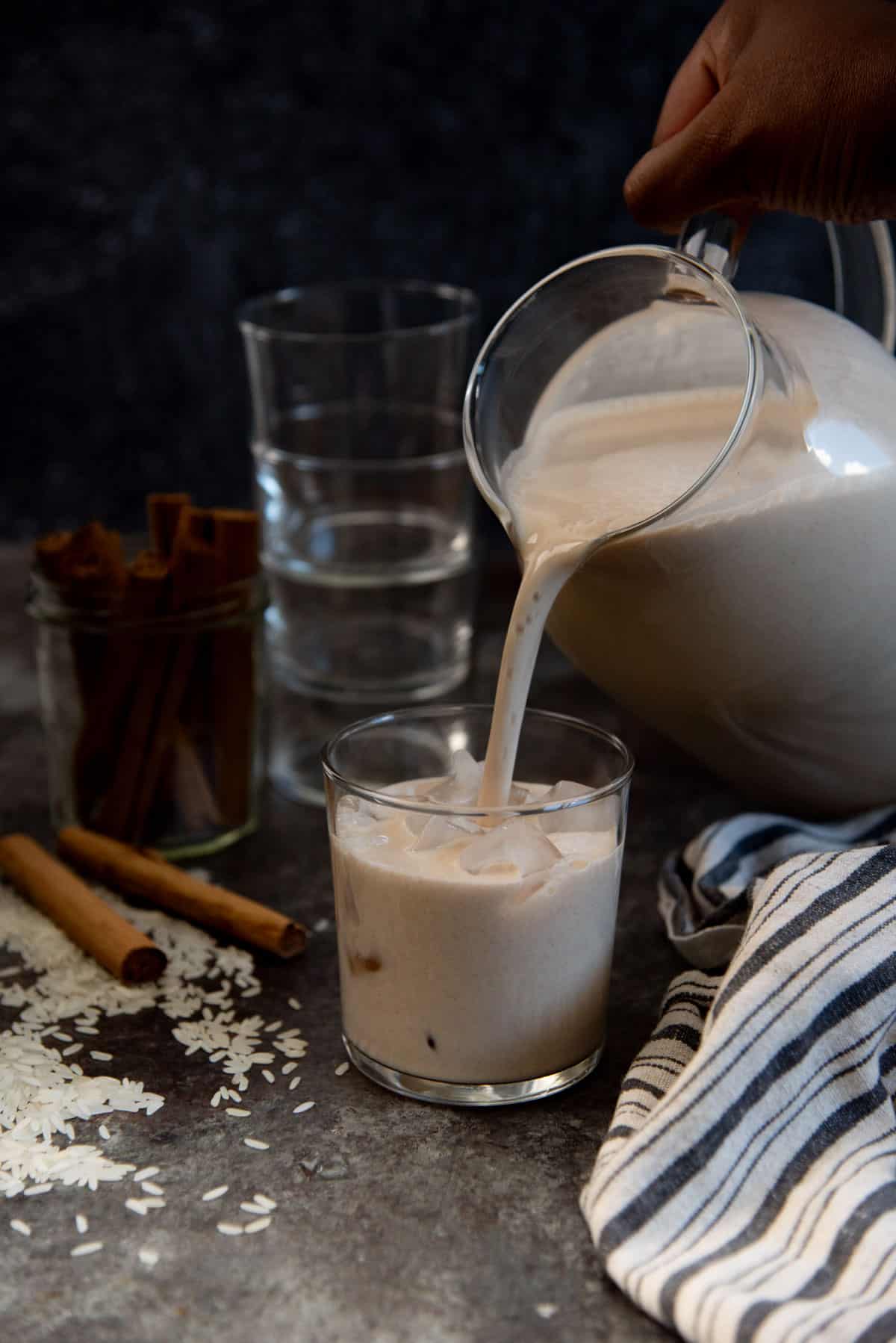 Pouring chilled horchata into an ice filled glass.