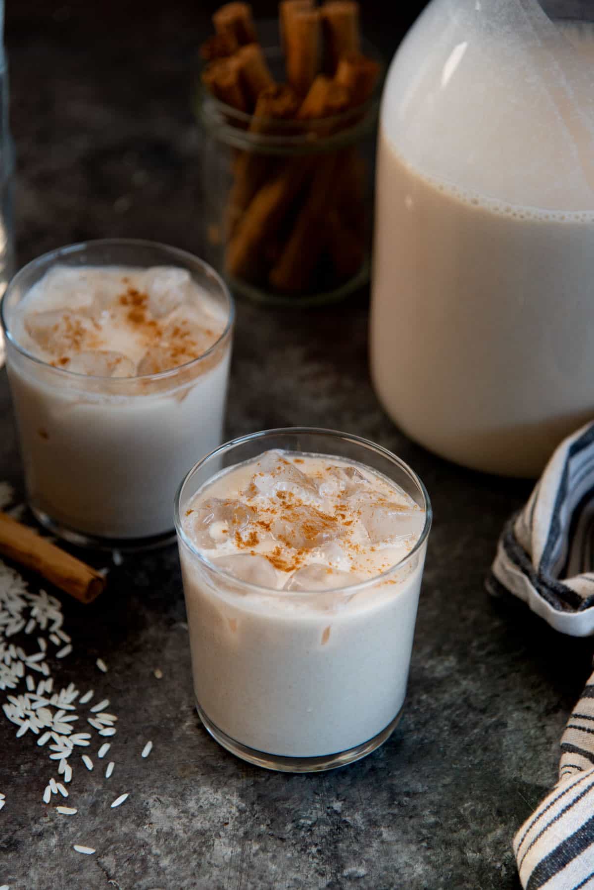 Close up of two serving glasses with ice, filled with Mexican horchata.