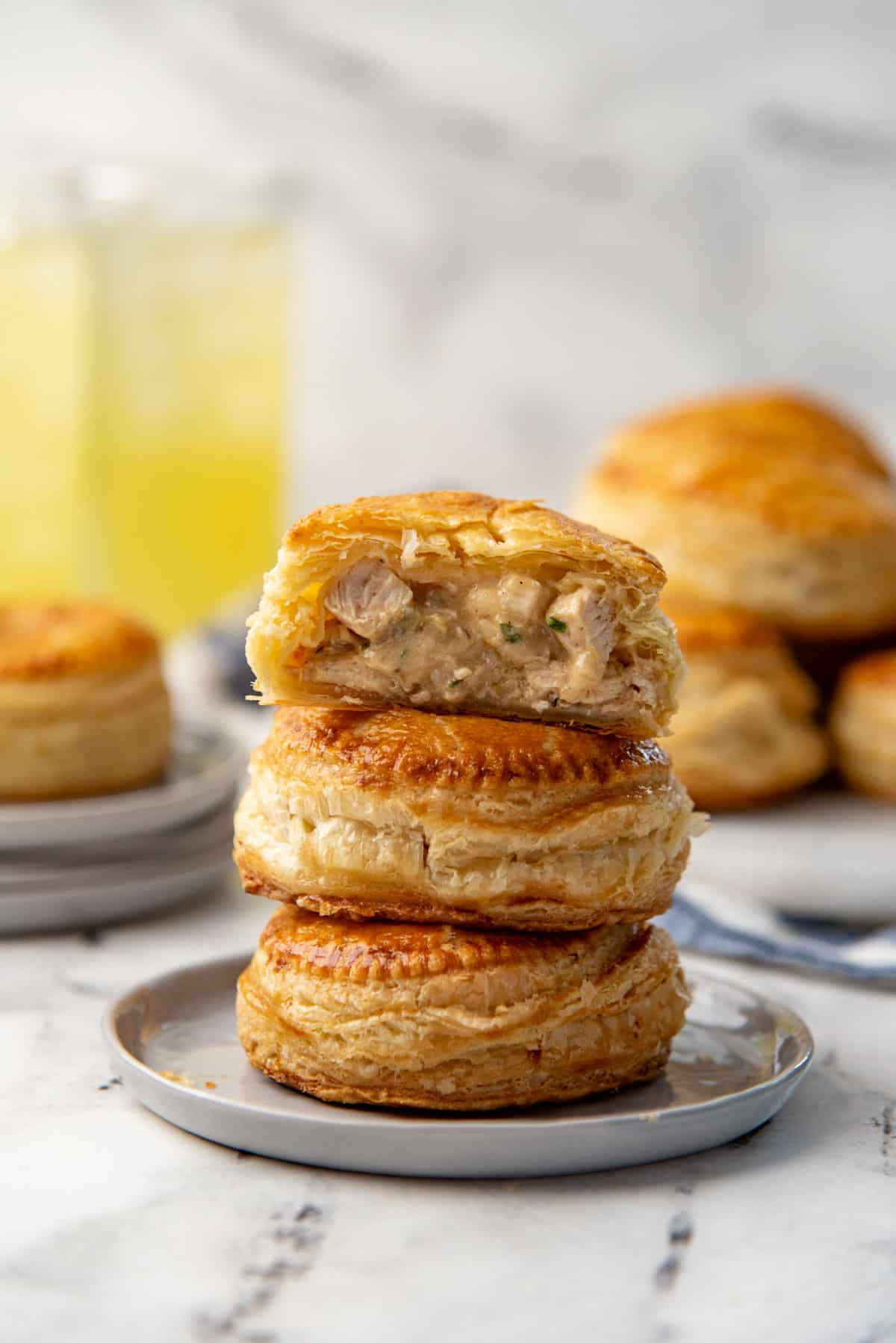 A mini chicken pie cut in half and stacked on top of two other flaky mini hand pies.