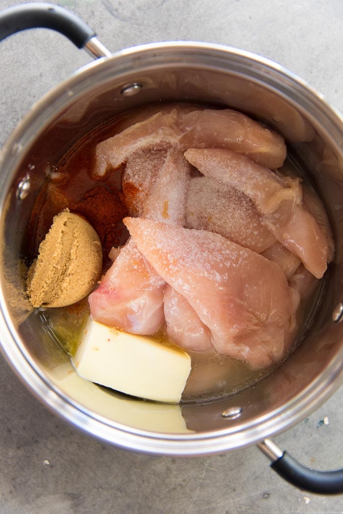 Chicken tenders placed in a saucepan with other ingredients to make the citrus chicken filling for taquitos