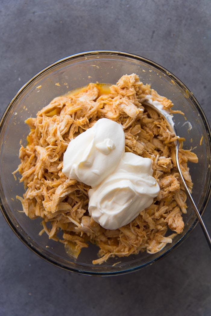 Shredded citrus chicken in a bowl, with crema agria on top.