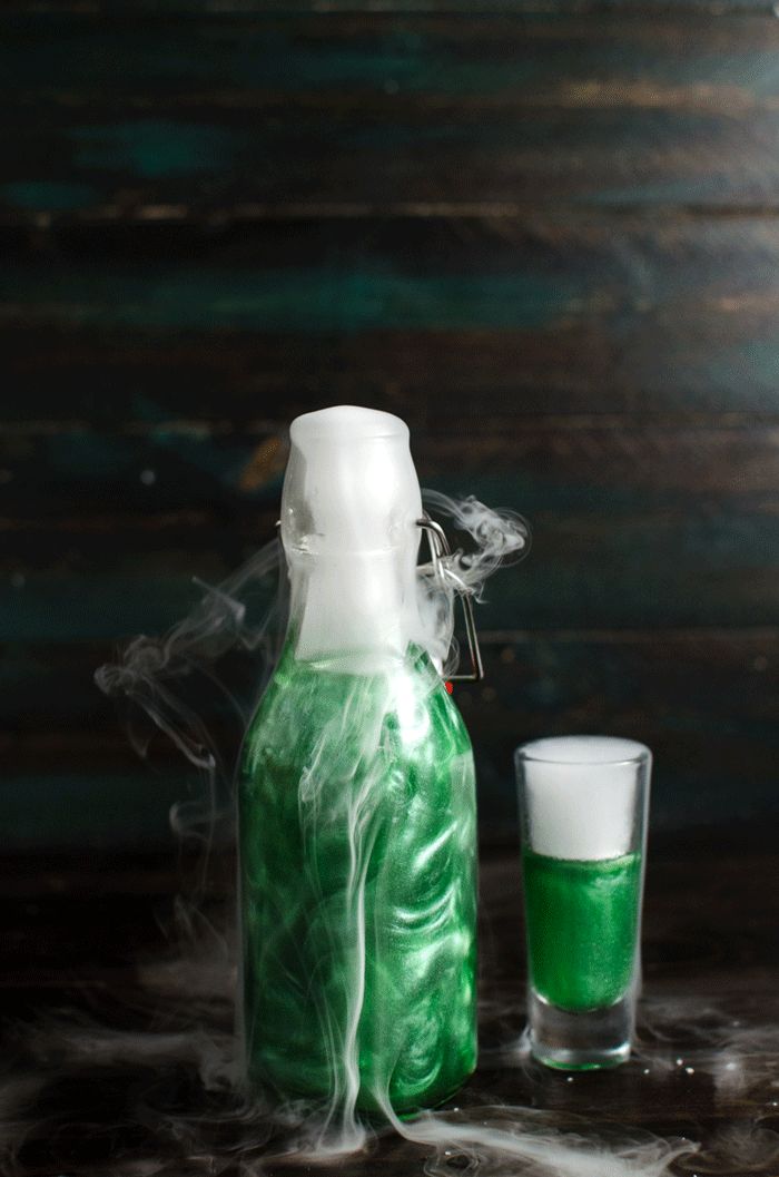 GIF of a bright green colored shimmering liqueur bottle with liquid nitrogen-induced smoke coming from the top.