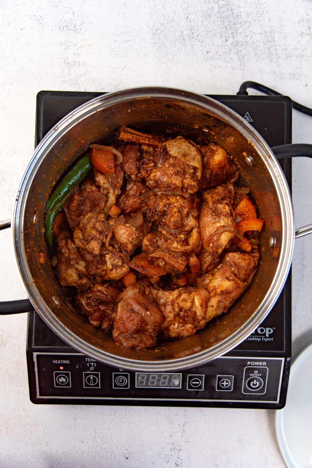 After mixing chicken with the spices before being simmered.