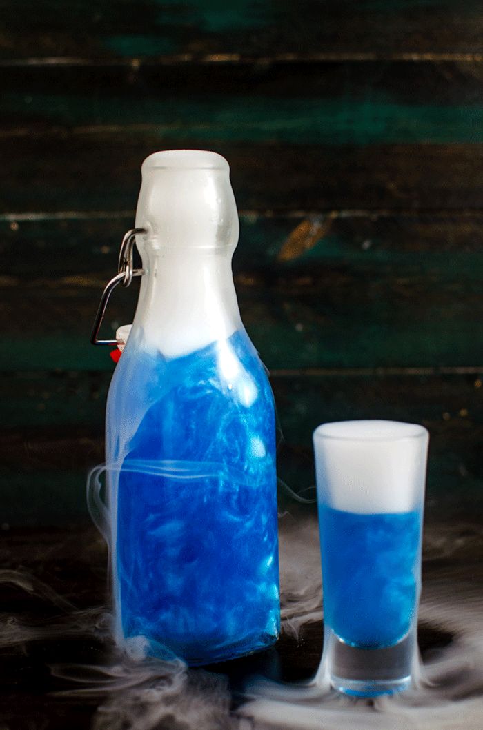 GIF of a bright blue colored shimmering liqueur bottle with liquid nitrogen-induced smoke coming from the top.