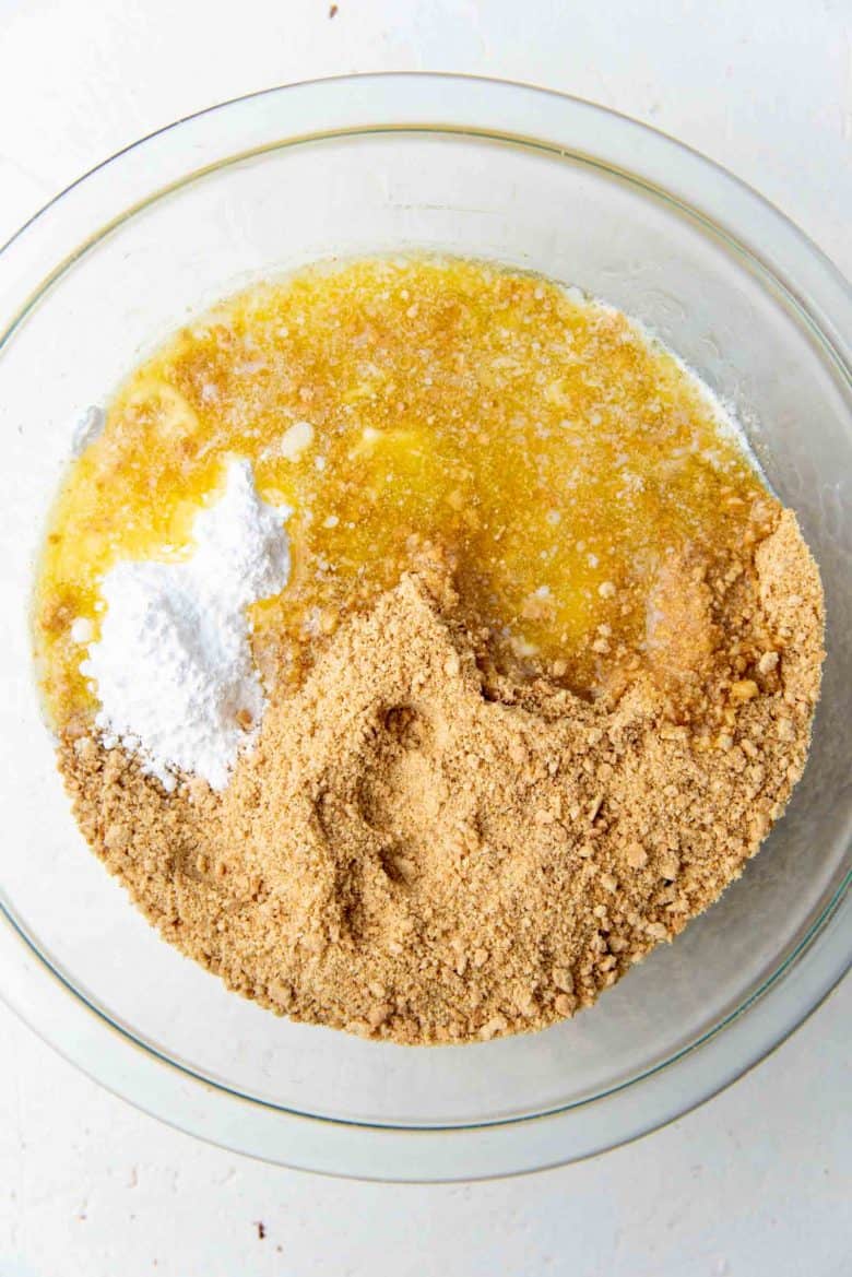 Melted butter added to the bowl of crushed graham cracker crumbs to make the cheesecake crust