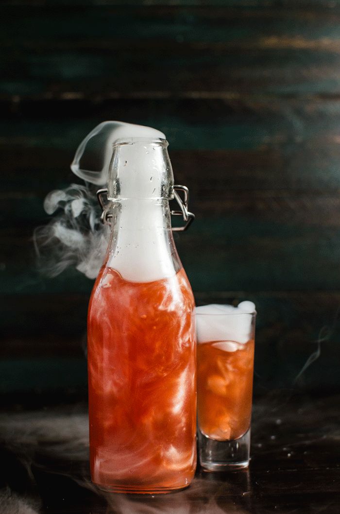 GIF of a bright orange shimmering liqueur bottle with liquid nitrogen-induced smoke coming from the top.