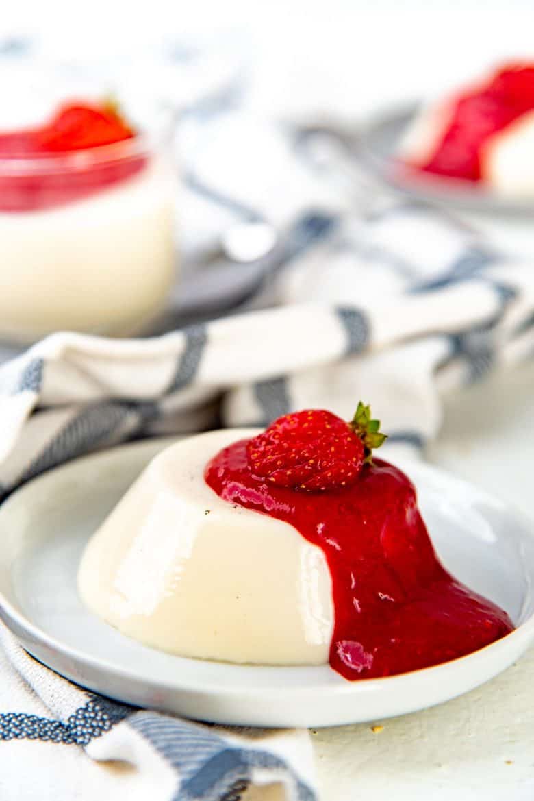 unmolded vanilla panna cotta served on a serving plate with berry coulis gel