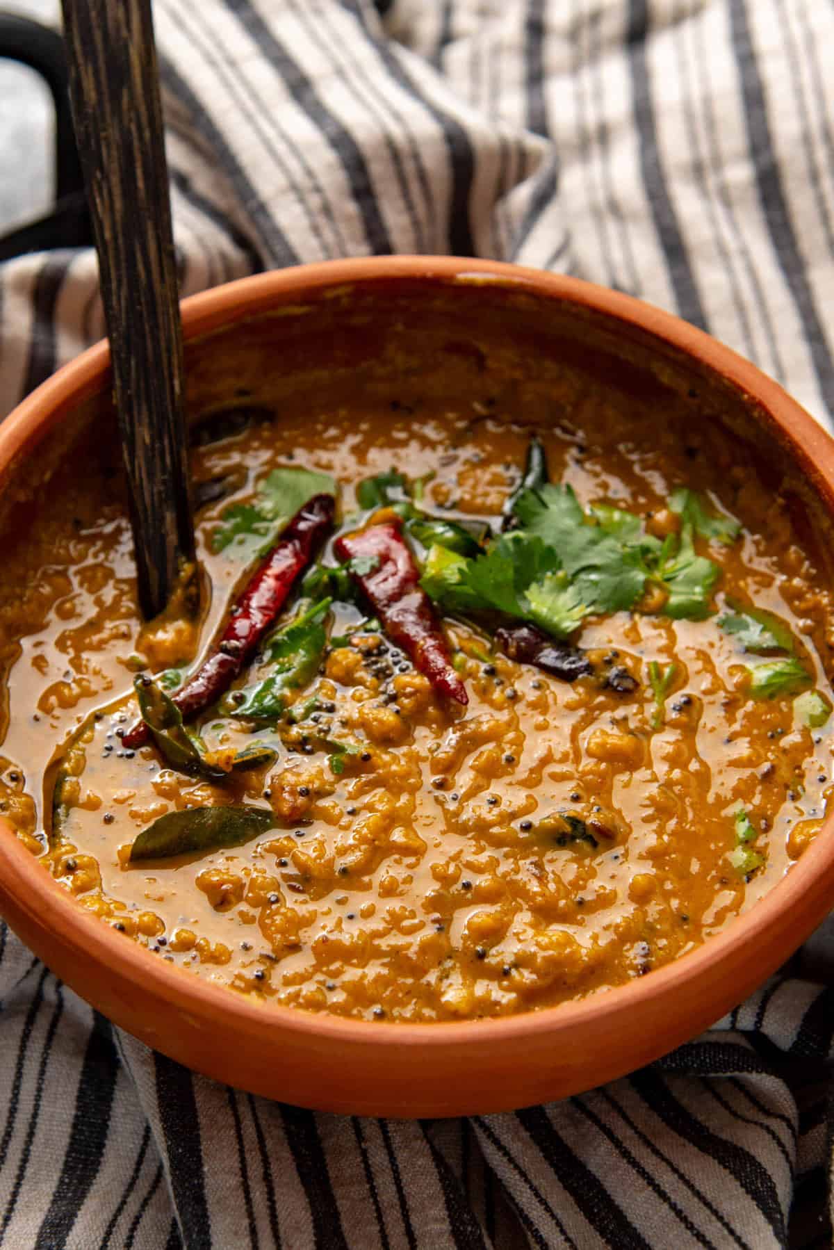 Close up of Sri Lankan red lentil curry made with coconut milk served in a clay pot.