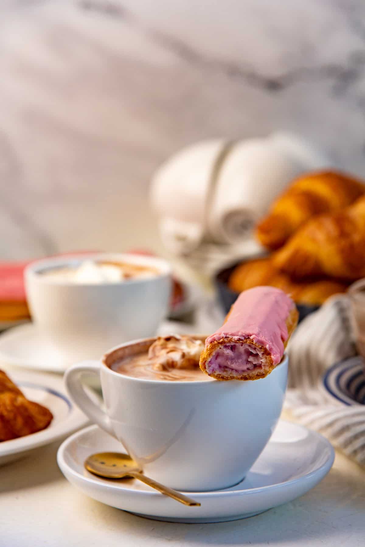 French hot chocolate served in a white mug, along with an eclair.