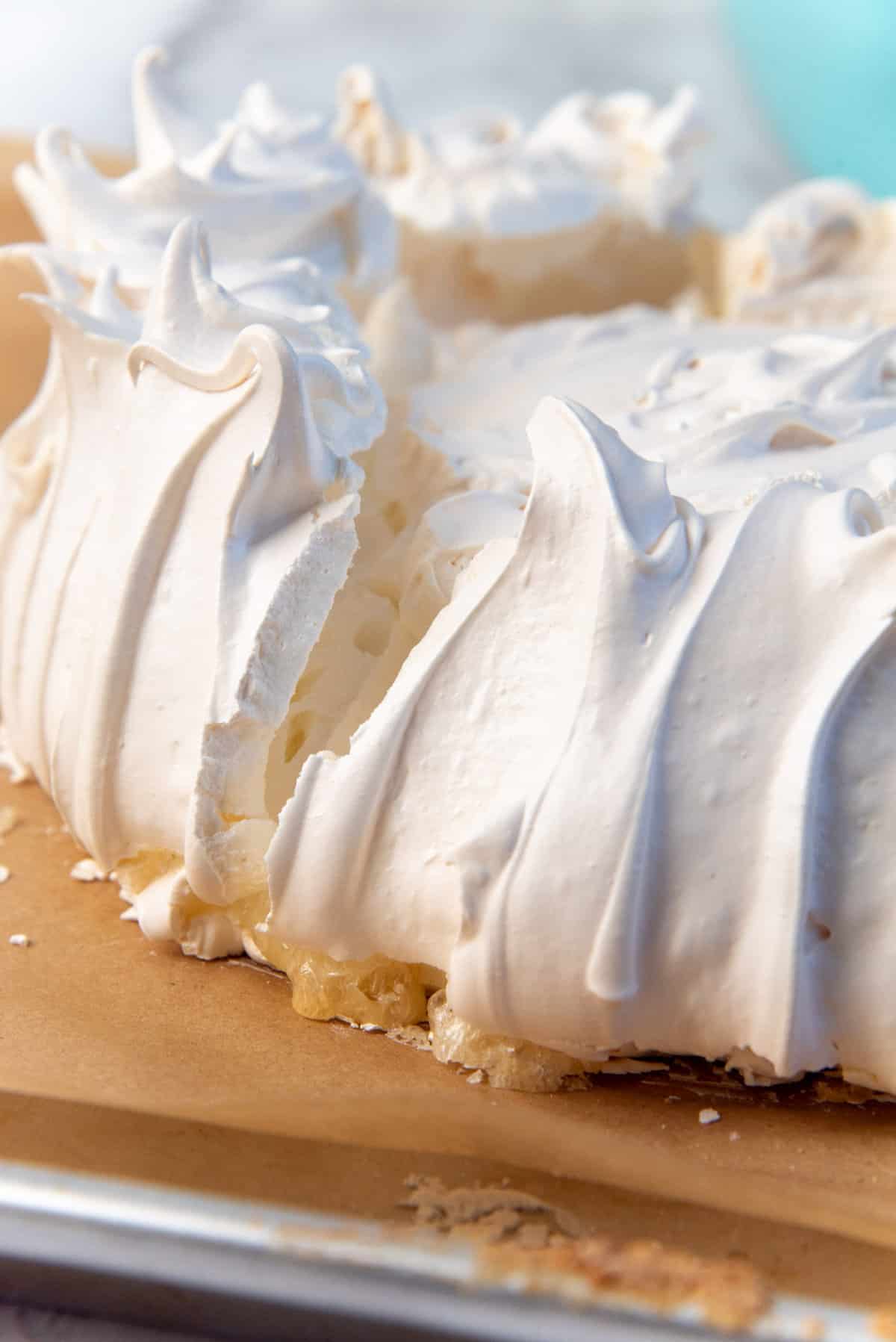 A close up of a pavlova that had gone wrong, showing a cracked pavlova crust, and sugar weeped below the crust.