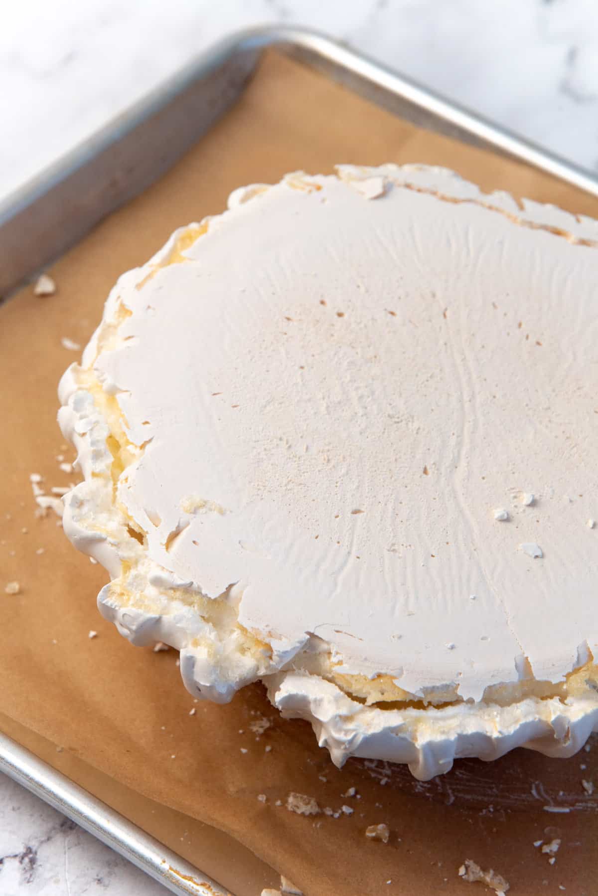 An image of a pavlova turned upside down, to show the large crack all along the bottom of the pavlova, a result of over whisked meringue.