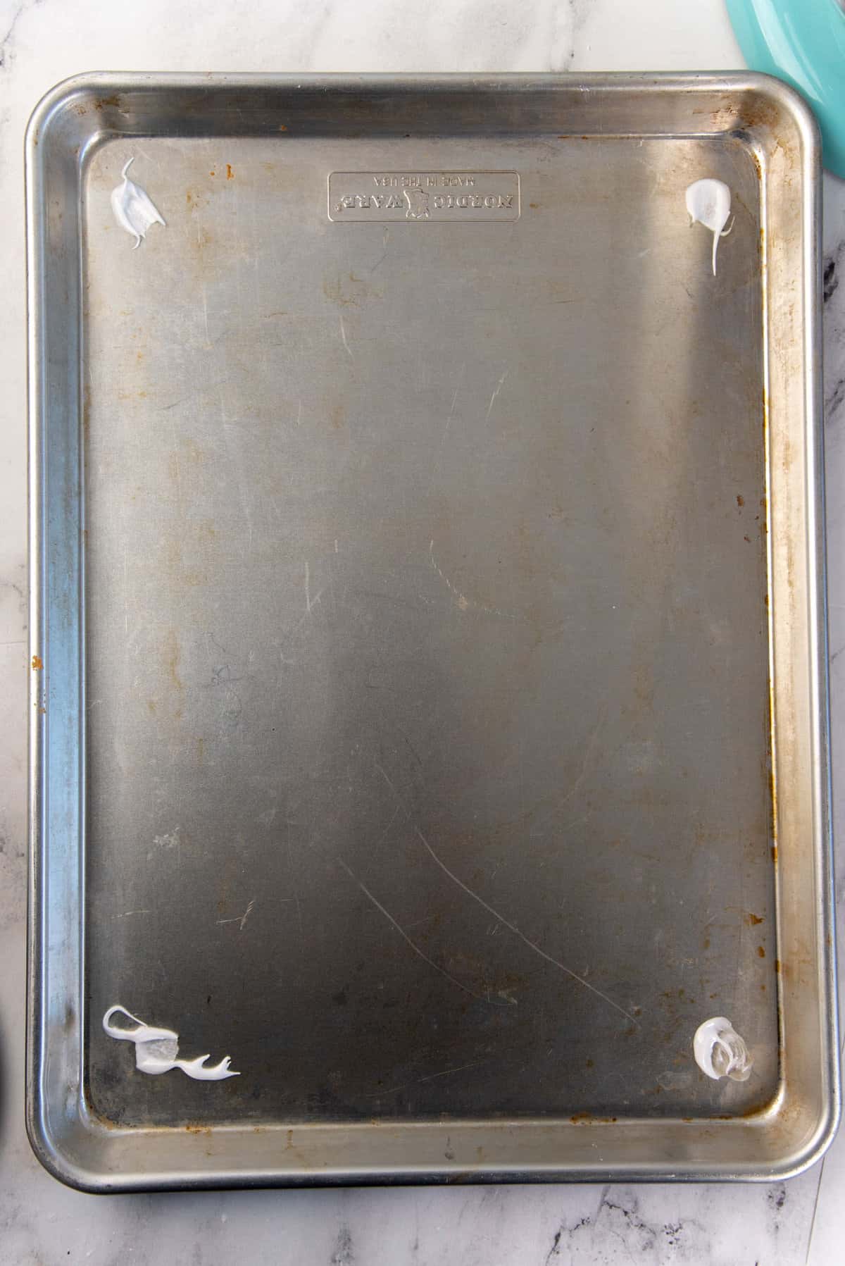 An overhead view of the half sheet pan baking tray, with meringue dabbed on the four corners.