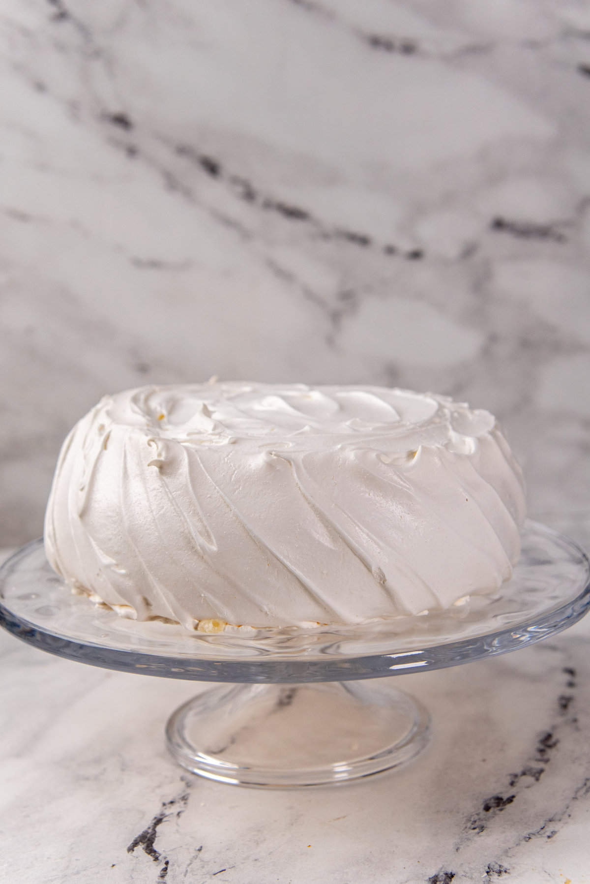 The cooled pavlova placed on a glass cake stand for serving.