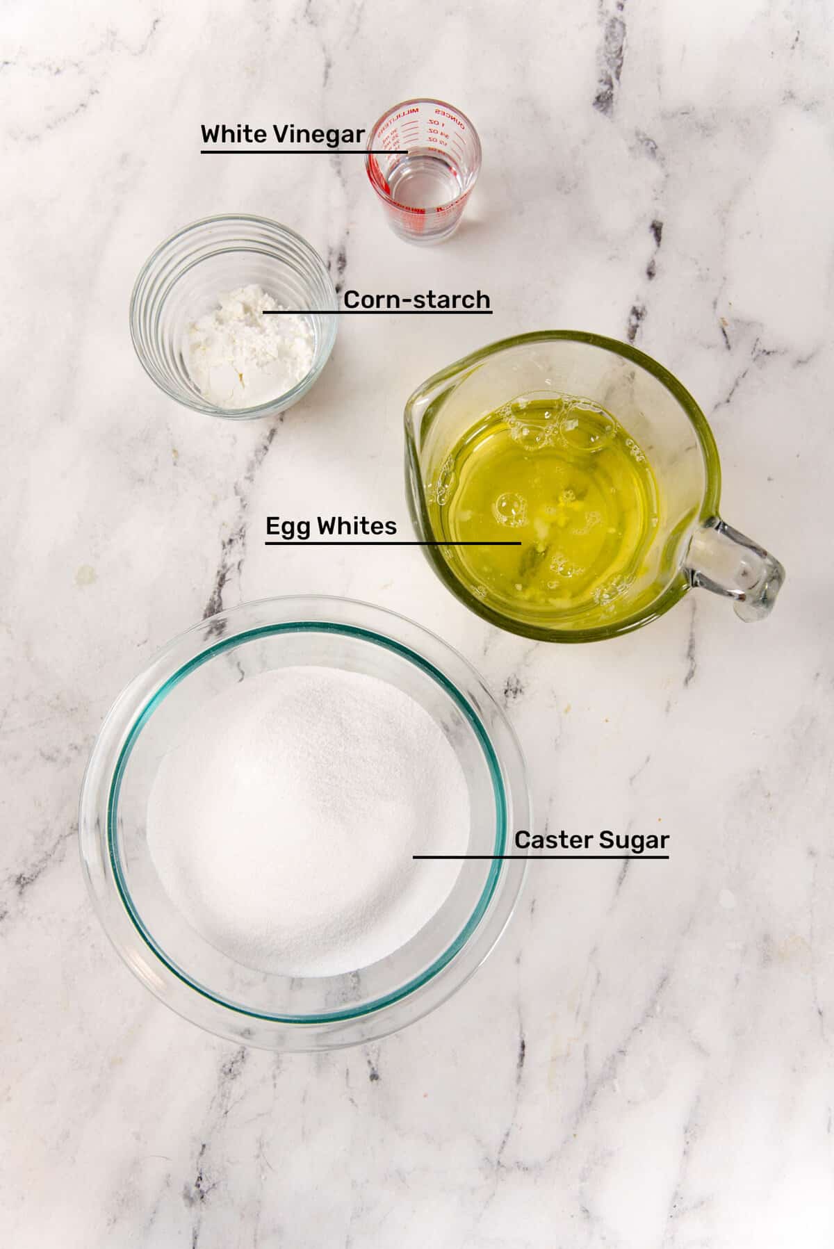 An image of the ingredients needed to make the pavlova base. From the top, white vinegar, cornstarch, egg whites and caster sugar.