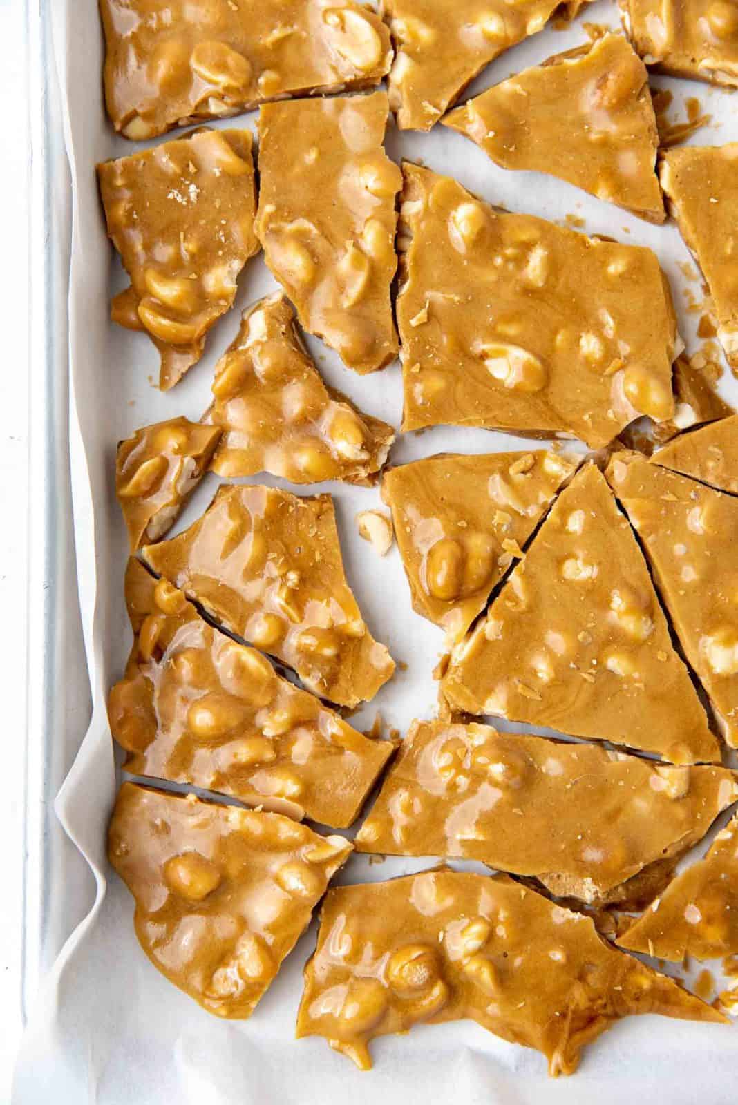 A close up of the cracked nut brittle on the baking sheet