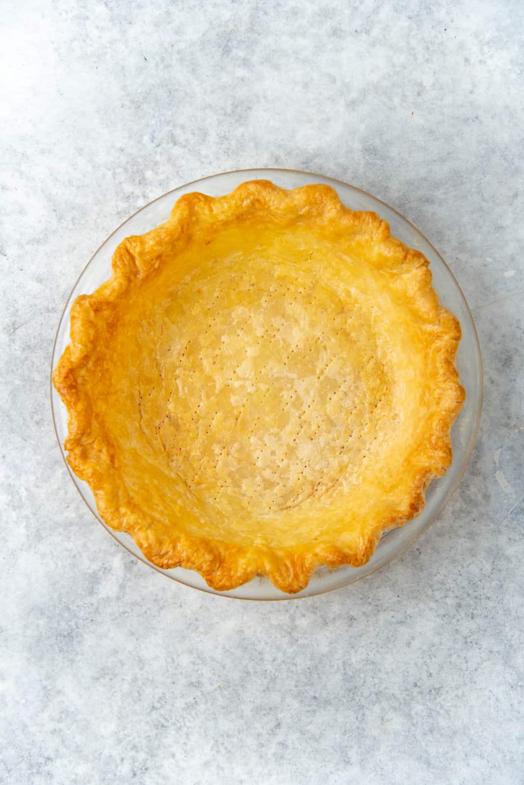 A blind baked full baked pie crust that is evenly golden colored.