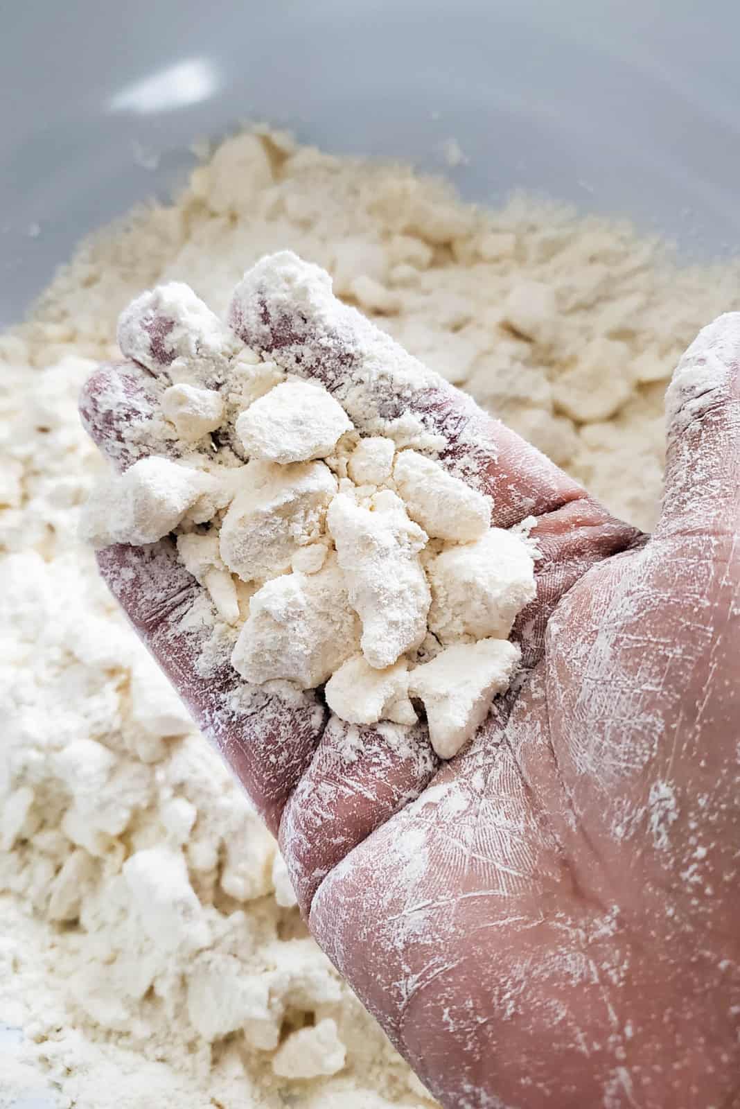 Butter and flour help in a hand to show the large clumps needed for a flaky pie dough.
