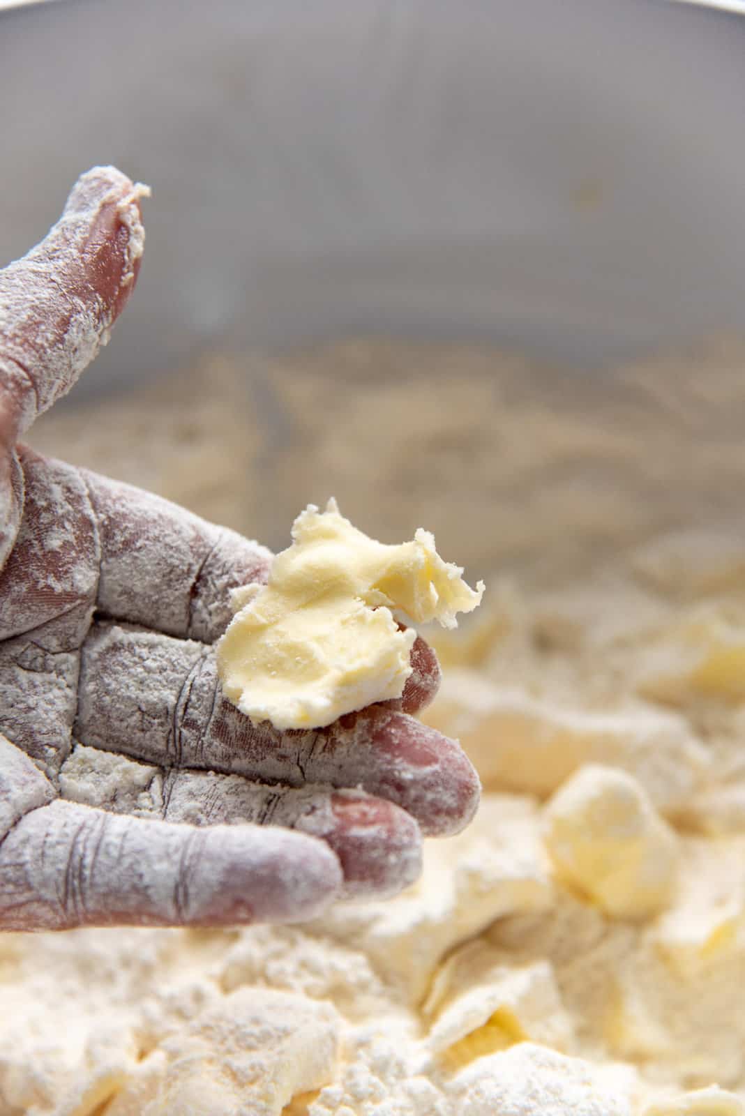 A piece of flattened butter held up by a hand.