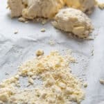 The dough clumped up into several balls in the background, with some dry flour in the foreground.