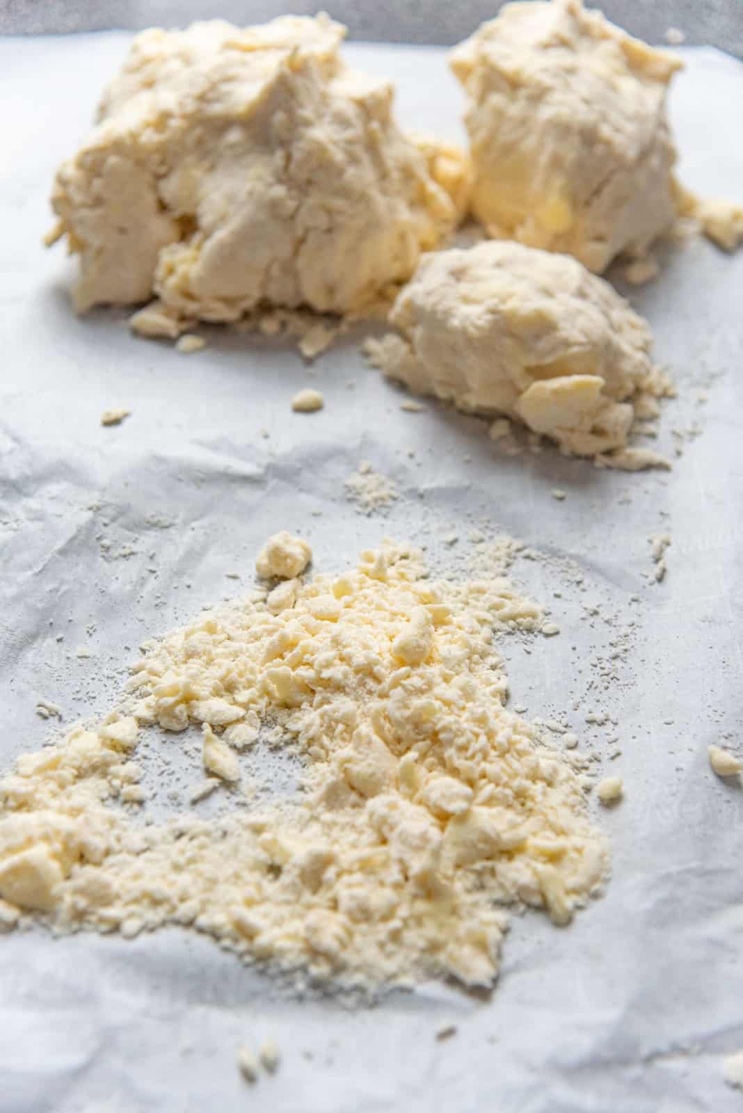 The dough clumped up into several balls in the background, with some dry flour in the foreground.