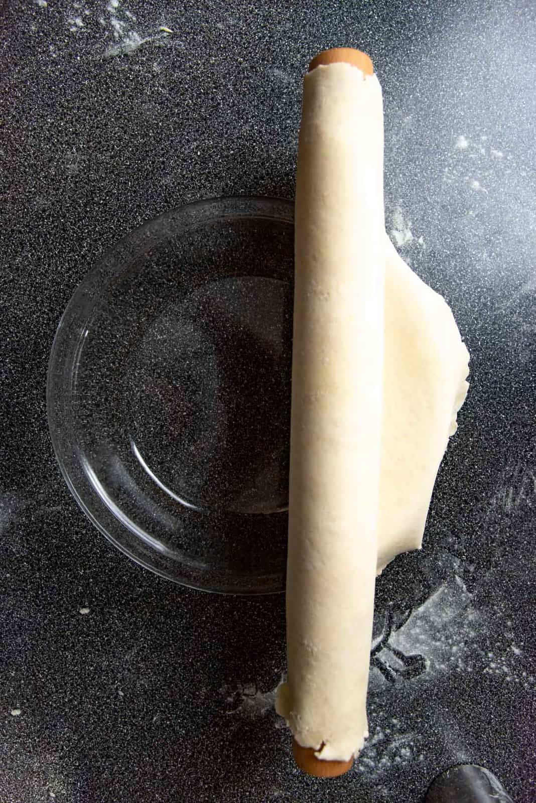 unravelling the pie dough over the pie dish.