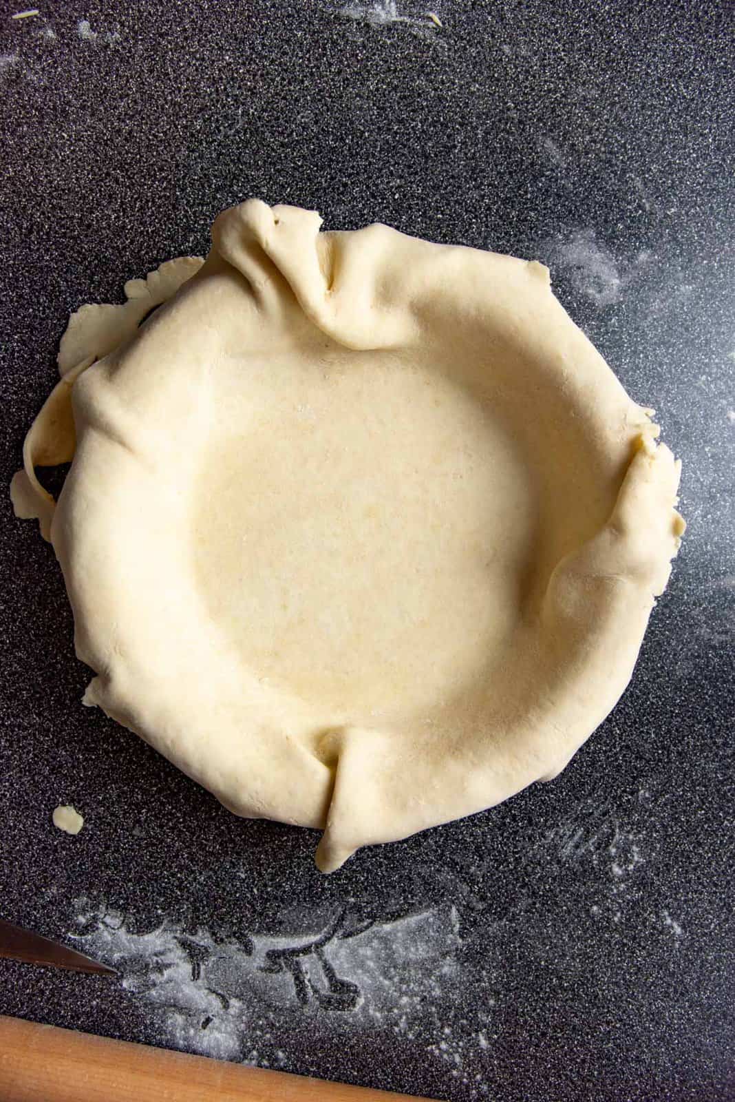 Overhead view of pie dough that has been fitted into a pie dish without stretching.