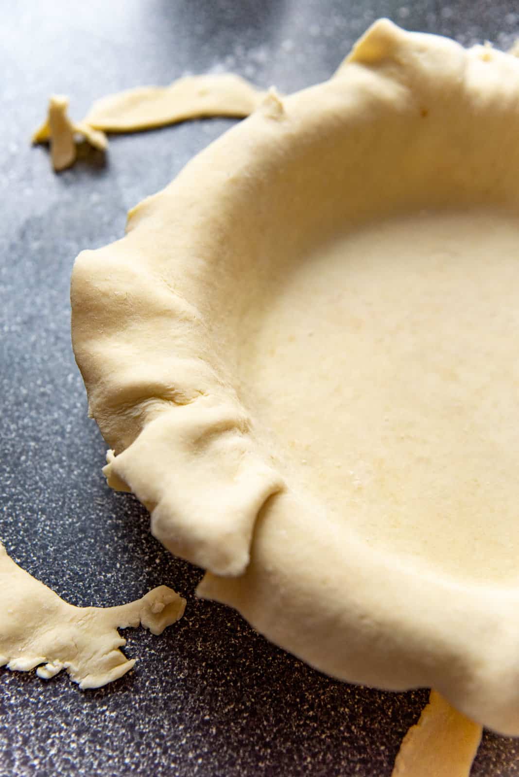 A close up of the pie dough in the pie plate, after the edges have been trimmed.