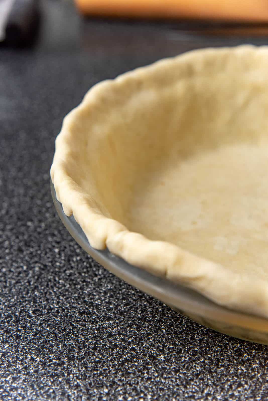 A view of the pie crust that has been rolled under to form a thick border at the edge of the pie pan.