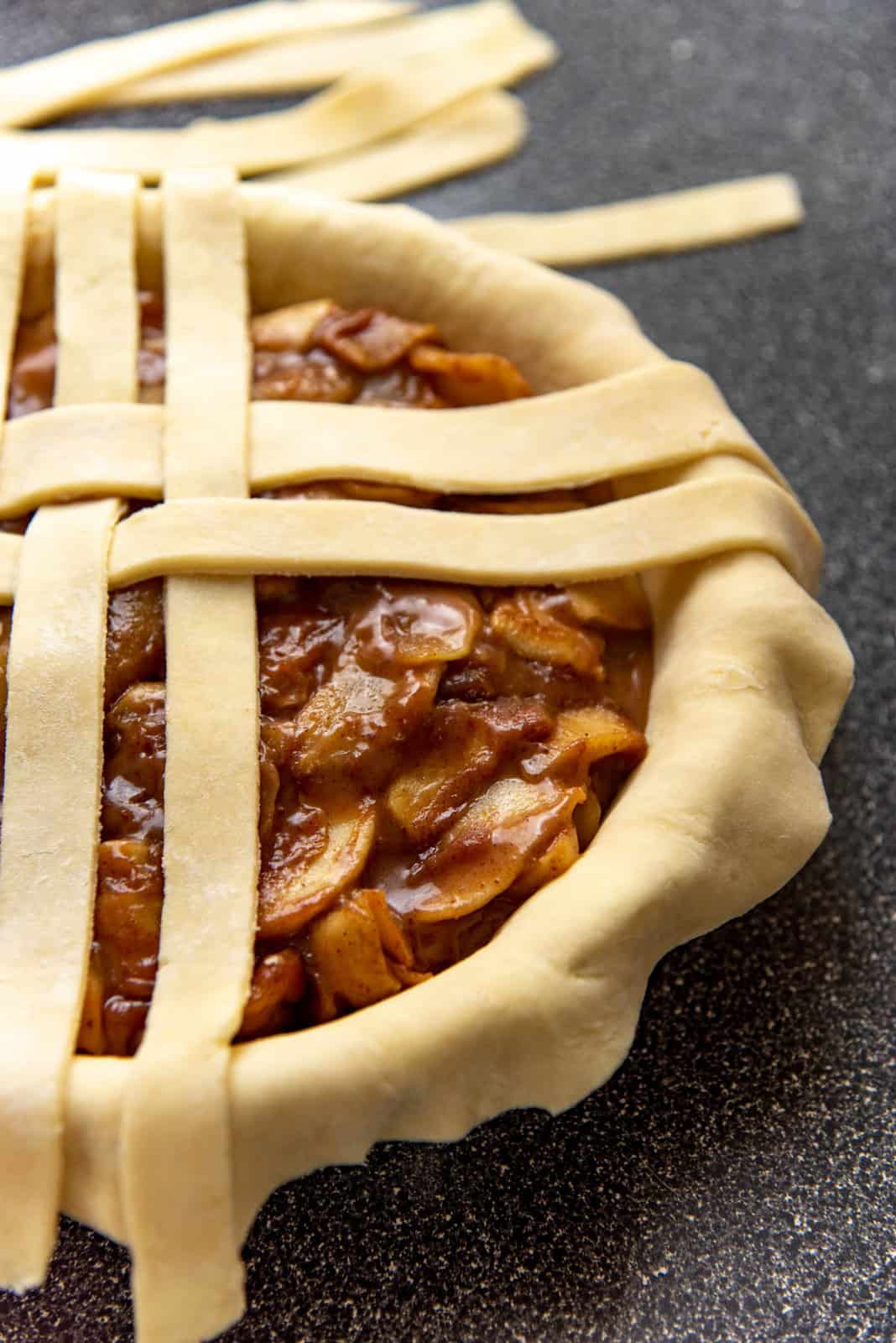 A double crusted pie, with a filling and a half finished lattice top.