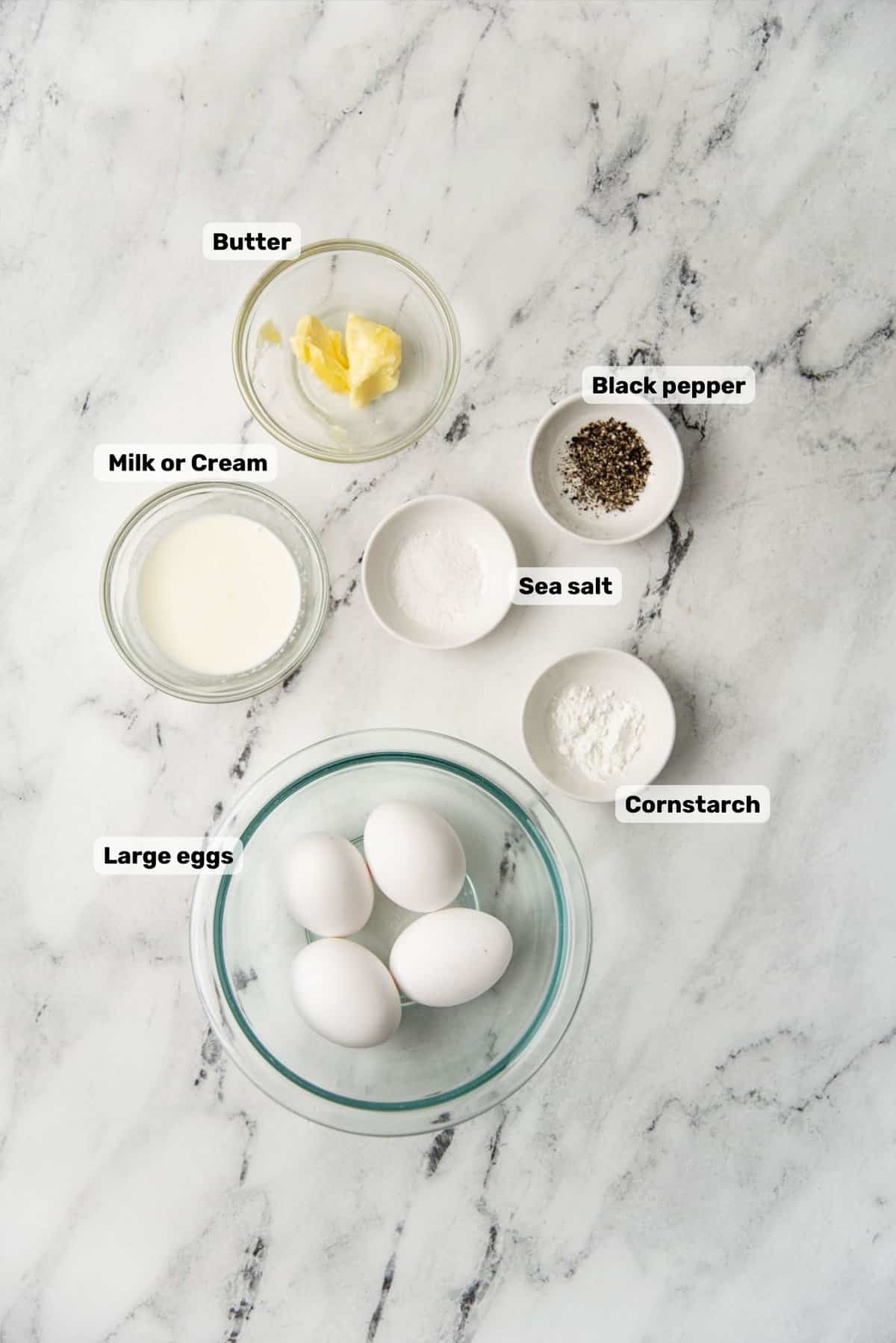 Ingredients needed to make creamy scrambled eggs with labels.