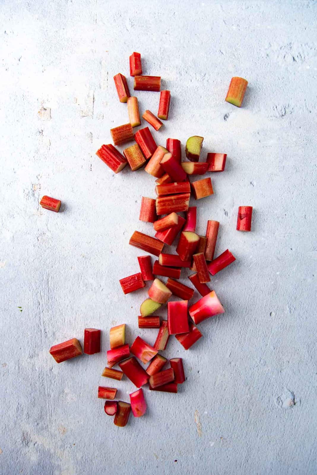 Rhubarb cut into pieces on a white surface.