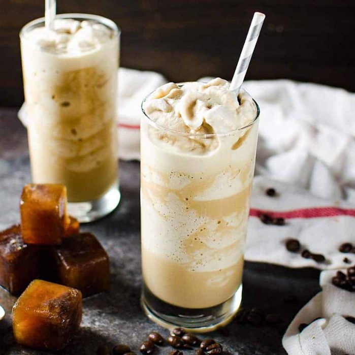 Coffee slushie served in a tall glass with a straw, and with coffee ice cubes next to it.