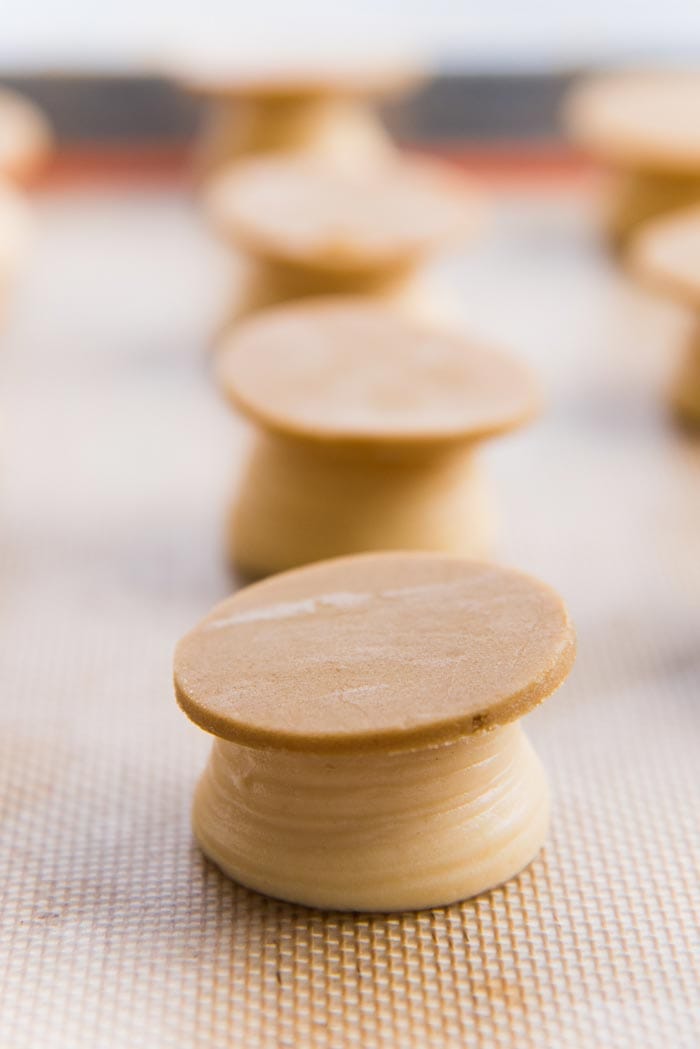 Craqueline discs placed on top of piped choux pastry dough