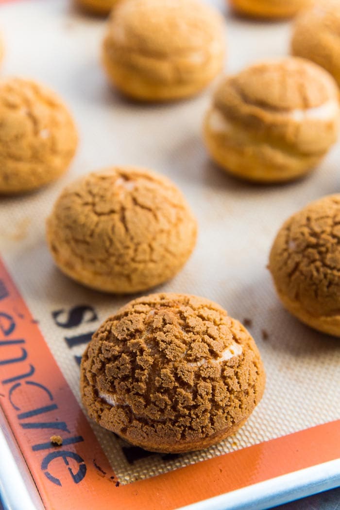 Freshly baked choux au craqueline on the baking tray, showing the crackly, crispy cookie surface