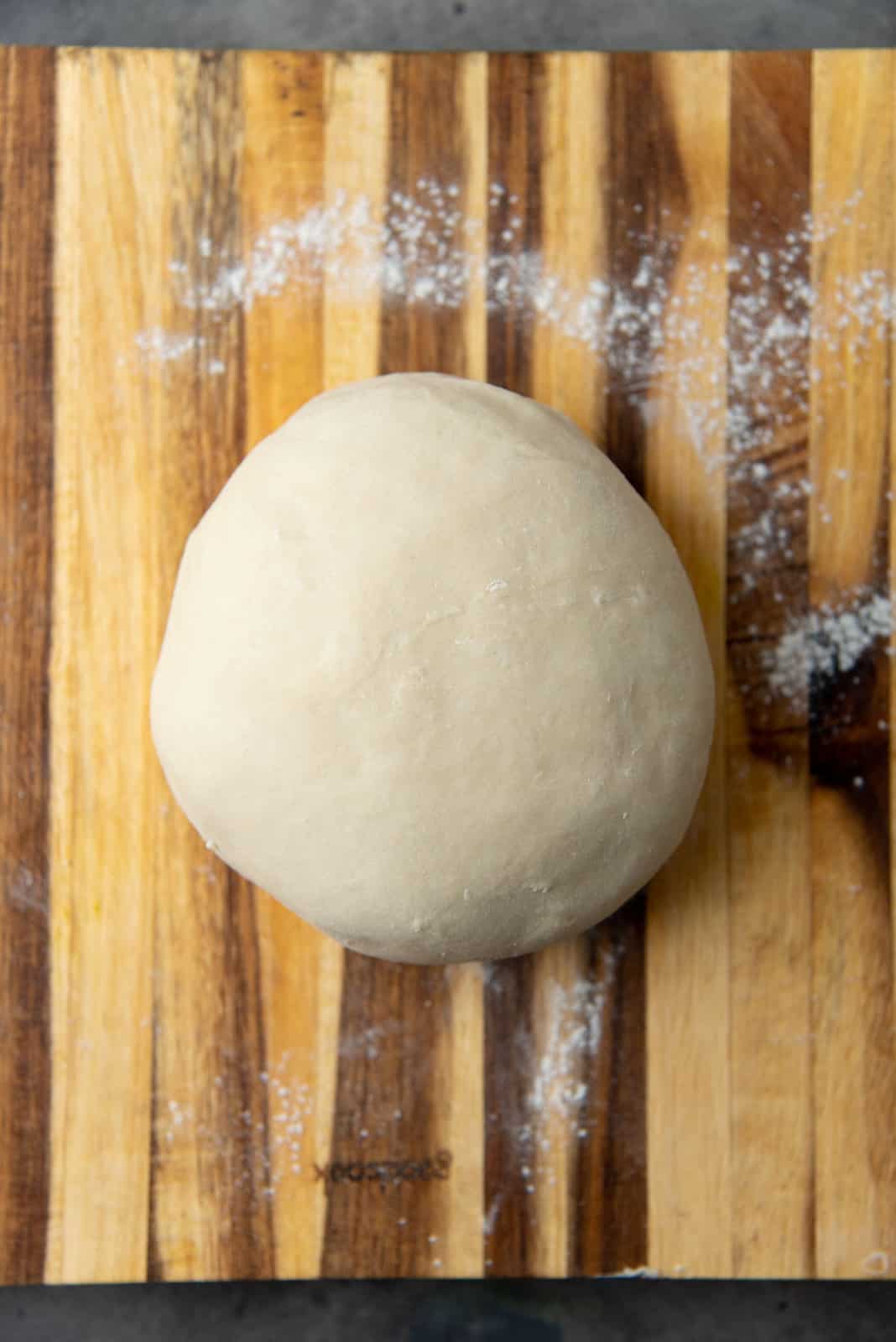 The water dough on a wooden board after kneading.