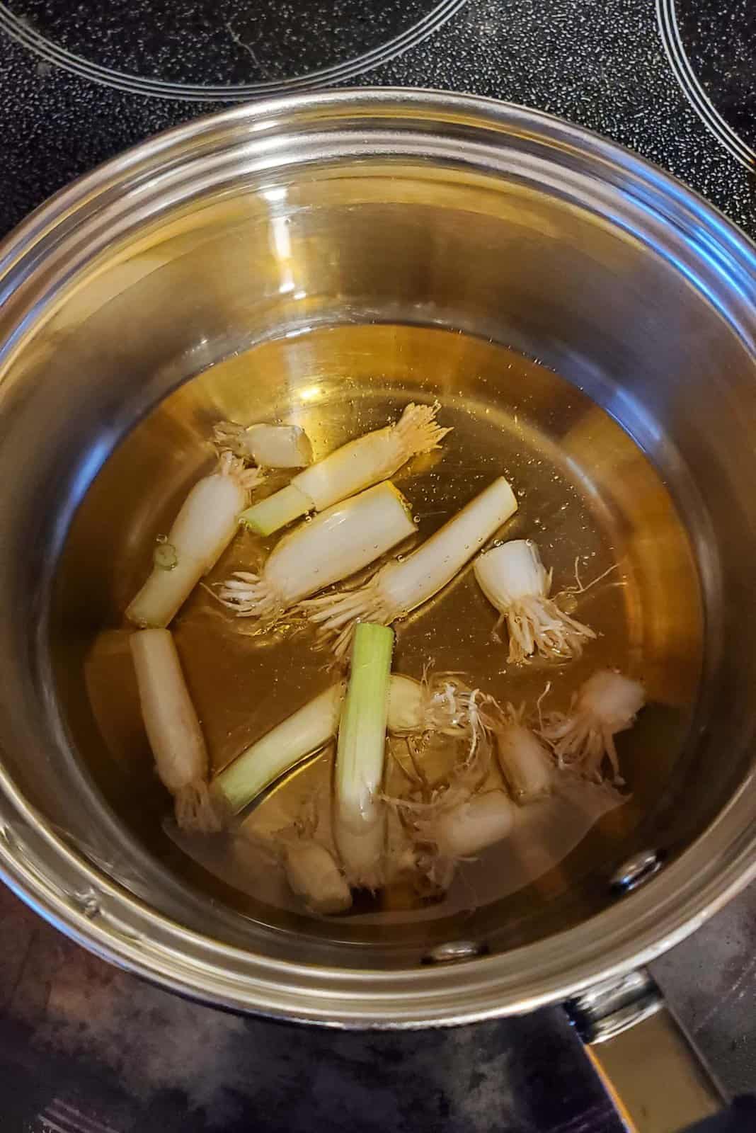 An image of a small pot, with oil and scallion ends inside.